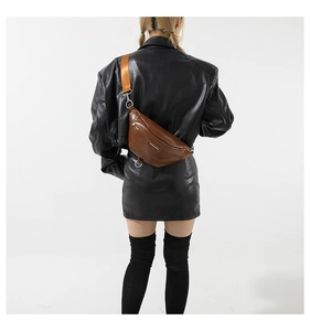 Close-up of brown glossy PU leather crossbody bag with wide orange nylon shoulder strap