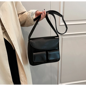 Detail of minimalist black PU leather shoulder bag with double front pockets and embossed text