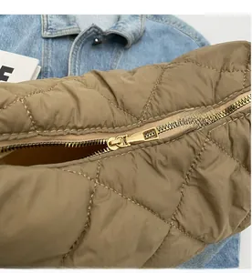 Detail of high-quality gold metal zipper on quilted khaki fabric shoulder bag