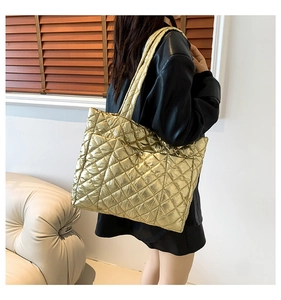 Detail of gold quilted tote bag with metallic finish showing large capacity on shoulder