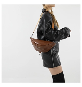 Detail of a brown PU leather crossbody bag with an orange woven strap on a model