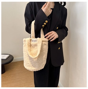 Detail of soft beige sherpa fleece texture and woven logo label on minimalist bucket bag