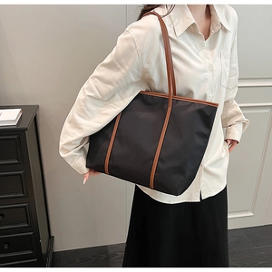 Lifestyle view of a large black nylon tote bag with brown straps on a fashion model
