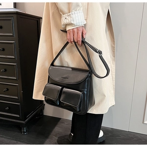 Detailed close-up of a black PU leather handbag featuring dual front flap pockets