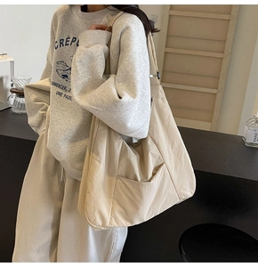 Vertical view of a beige nylon tote bag showing its side pocket and large capacity details