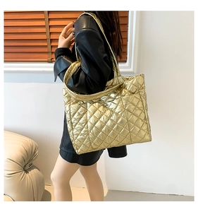 Detail of a large gold quilted tote bag with diamond stitching pattern for women