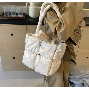 Detailed view of women white quilted puffer tote bag shown on model in modern room