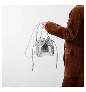Detail of silver metallic bucket bag with drawstring closure and cross logo detail