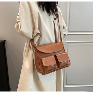 Detail of a brown PU leather crossbody bag featuring functional front pockets and wide strap