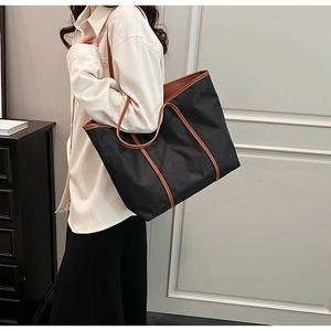 Close-up of black nylon tote bag with brown leather handles for daily commuting