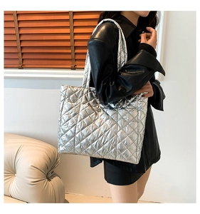 Detail of silver quilted tote bag with metallic finish shown on model in a modern room