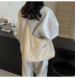 Detailed view of beige nylon shoulder bag with vertical stitching and front pocket