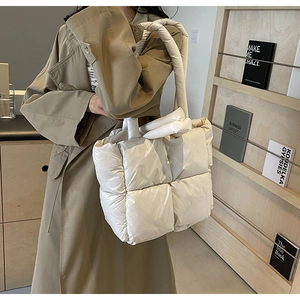 Detailed view of a white quilted down puffer tote bag paired with a classic khaki trench coat