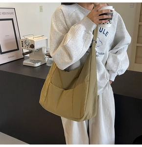 Close-up of khaki nylon shoulder bag with side pocket shown in a lifestyle cafe setting