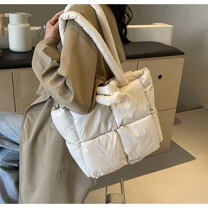 Detail of white quilted puffer shoulder bag with soft nylon texture on khaki coat