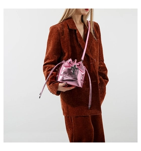 Detail of metallic pink bucket bag with black cross pattern worn by model