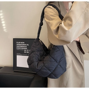 Detail of black quilted shoulder bag with unique knotted strap and puffy fabric texture