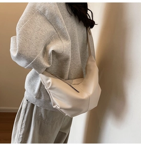 Dettaglio della borsa a mezzaluna beige in pelle PU con morbide pieghe e trama opaca