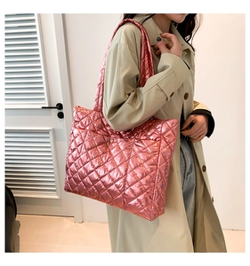 Close-up of pink metallic quilted tote bag with wide strap on a model wearing a beige coat