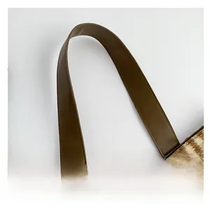 Dettaglio del manico in pelle marrone su borsa in lana a righe marroni e bianche