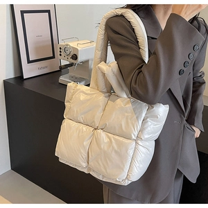 Detail of cream quilted puffer tote bag in glossy nylon fabric for winter fashion