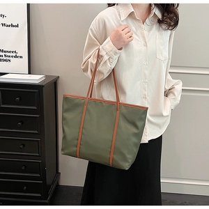 Close-up of green nylon tote bag with brown leather straps shown on a female model