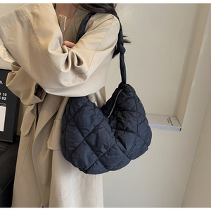 Detail of black quilted puffer tote bag showing diamond stitching and knotted strap design