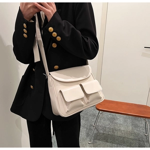Close-up of cream PU leather crossbody bag featuring dual front pockets and curved flap