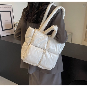 Detailed back view of a large beige quilted down tote bag worn with a brown blazer