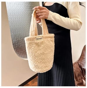 Close-up of beige plush tote bag featuring an AOHUDIE brand label on soft faux fur fabric