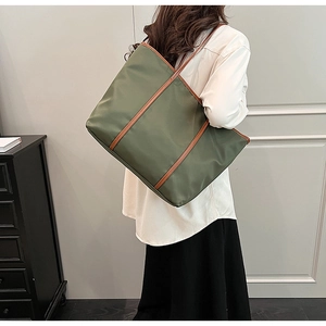 Olive green nylon tote bag with brown leather straps worn by model in a minimalist setting