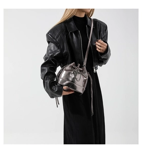 Detail of trendy metallic silver bucket bag with drawstring closure shown on model