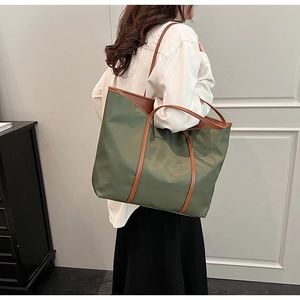 Olive green nylon tote bag with brown leather handles worn by a model in casual setting