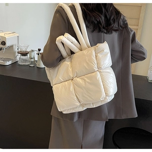 Quilted down nylon tote bag in off-white shown on a model in a cozy cafe setting