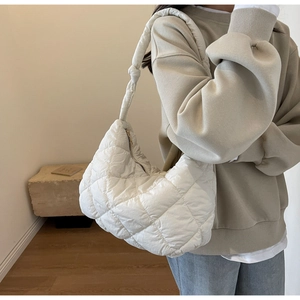 Close-up of white quilted puffer shoulder bag styled with casual grey sweatshirt and jeans