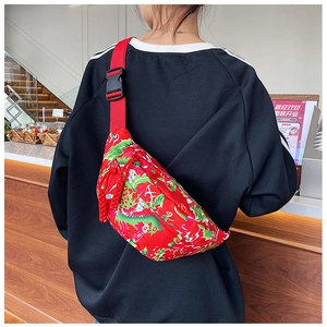 Close-up of winter crossbody bag with traditional red floral pattern and black buckle