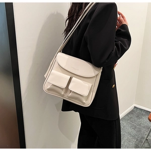 Detail view of cream white PU leather shoulder bag with symmetrical front flap pockets
