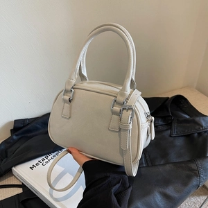 Detail shot of the cream-colored PU leather handbag with dual handles and silver buckle