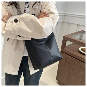 Detail of black lychee texture PU leather tote bag with white vertical contrast stitching