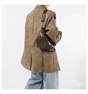 Detail view of dark brown crescent bag with wide nylon strap on model's shoulder