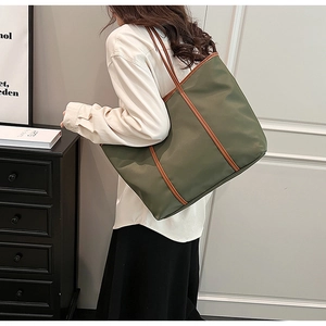 Detail of olive green nylon tote bag with brown leather straps shown on a model