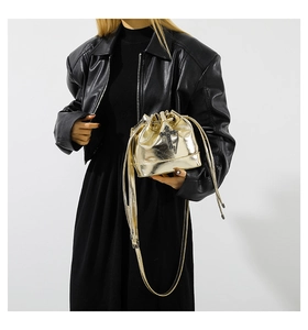 Detailed close-up of a gold bucket bag featuring black rhinestone cross and metal chains