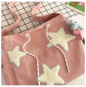 Detail van roze corduroy draagtas met pluchen sterren en trekkoordsluiting details