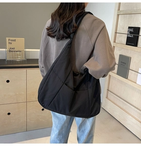 Quilted black nylon crossbody tote bag shown on a model in a minimalist studio setting