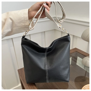 Detail of black pebbled leather tote bag featuring white stitching and jacquard strap