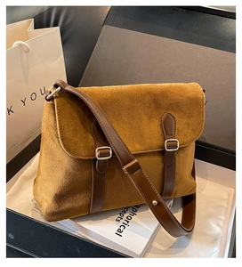Detail of tan suede messenger bag with dark brown straps and silver metal buckles