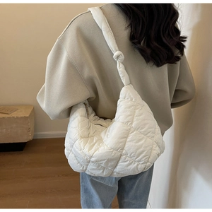 Detail showing white quilted crescent bag with puffer texture and knotted strap design