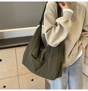 Detail of army green nylon crescent bag on model showing adjustable strap and large capacity