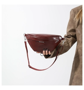 Detail of burgundy crescent moon chest bag with silver ring and adjustable strap
