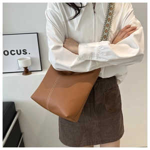 Detail of brown leather tote with white stitching and ethnic patterned strap